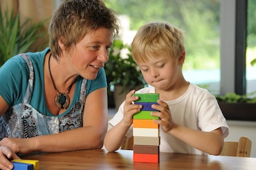 Teacher works with student stacking building blocks